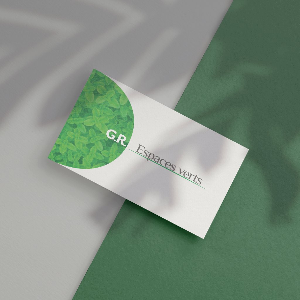 A G.R. Espaces verts business card on a grey and green paper, the half circle of foliage beside the words, in the shade of a leaf
